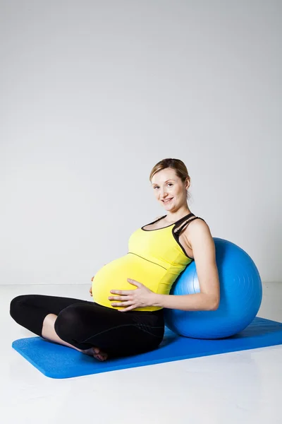Mujer embarazada relajándose contra la pelota de fitness —  Fotos de Stock