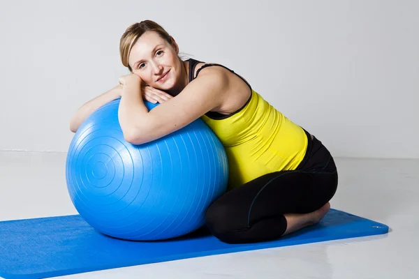Беременная женщина расслабляется против фитнес-мяч — стоковое фото