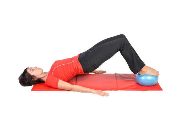 Fit young female pilates instructor showing different exercises with ball on a white background — Stock Photo, Image