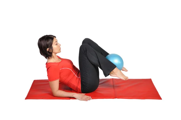 Ajuste joven instructor de pilates femenino que muestra diferentes ejercicios con pelota sobre un fondo blanco — Foto de Stock