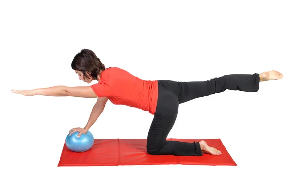 Passa unga kvinnliga pilates instruktör visar olika övningar med boll på en vit bakgrund — Stockfoto
