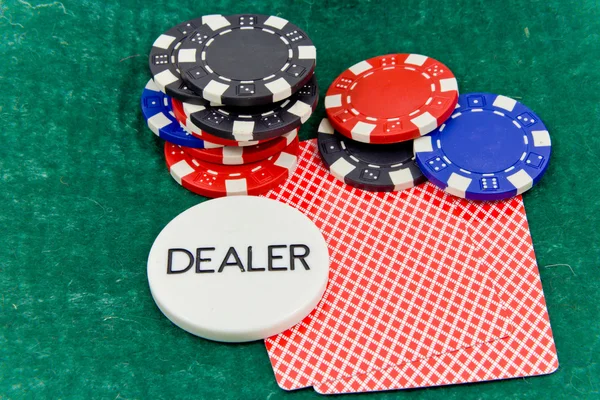 stock image Poker dealer button, chips and cards on green felt