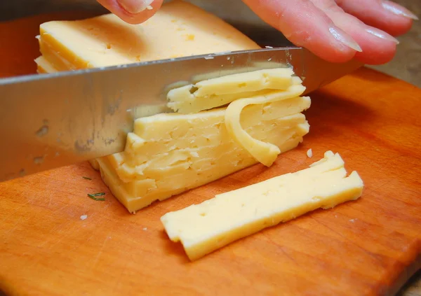 Сыр нарезают ножом на деревянной доске — Stok fotoğraf