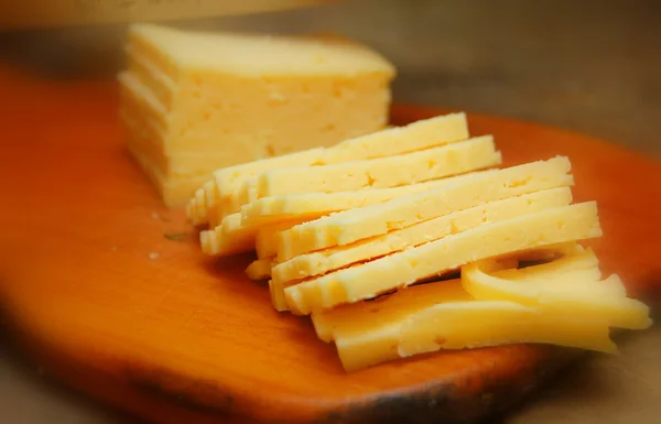 Нарезанный сыр на деревянной доске ストック写真