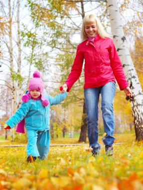 mutlu genç anne ve küçük kızı bir sonbahar parkında eğleniyor