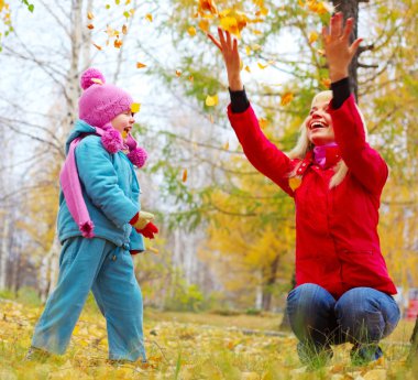 genç anne ve küçük kızı sonbahar bir ormanda ve having fun