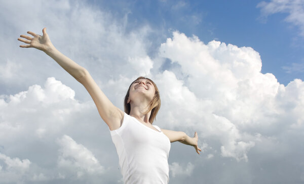 Smiling young woman in white shirt on cloudy sky background