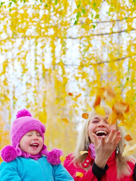 Jovem mãe feliz e sua filhinha se divertindo em um parque de outono — Fotografia de Stock