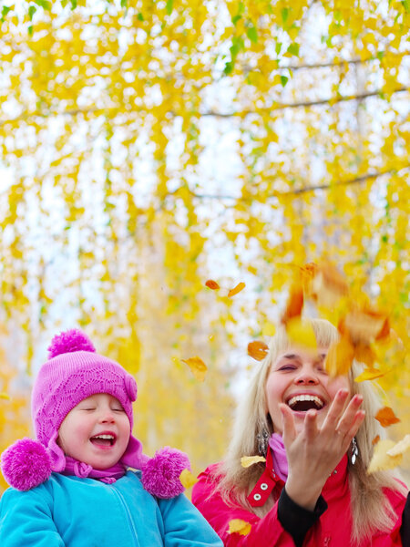 Happy young mother and her little daughter having fun in an autumn park
