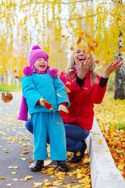 Happy young mother and her little daughter having fun in an autumn park — Stock Photo, Image