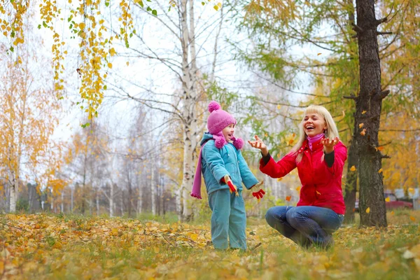 Młoda matka i córka trochę zabawy w lesie jesienią — Zdjęcie stockowe
