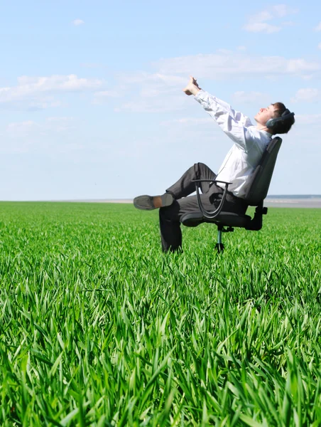 Uitrekkende man op stoel in groene veld — Stockfoto