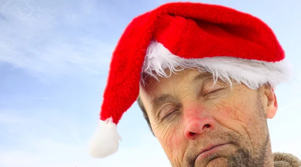 Drunk man in santa's hat over sky background — Stock Photo, Image