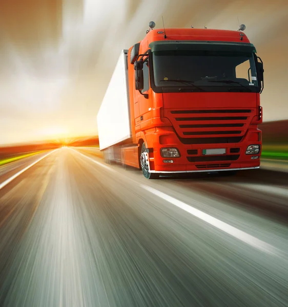 Red truck on blurry asphalt road and motion blured sky — Stock Photo, Image