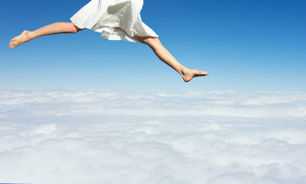 Woman in white dress jumping over sky