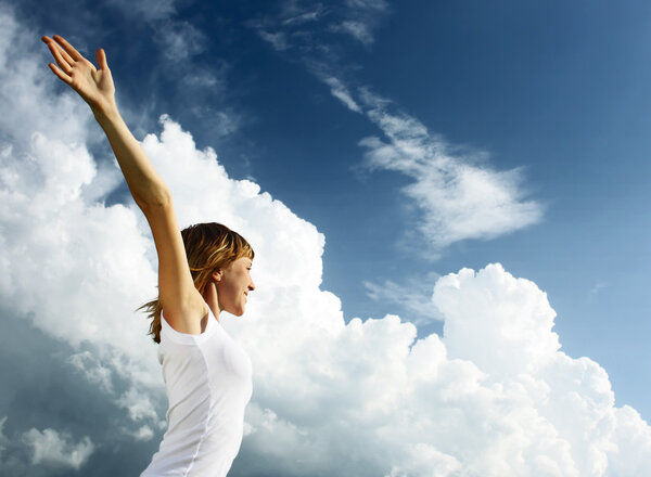 Young woman in white shirt over blue sky with fluffy clouds