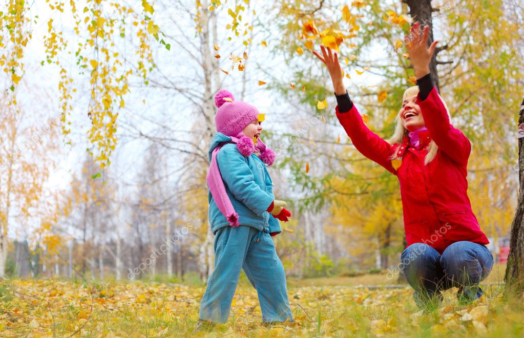 Young mother and her little daughter having fun in an autumn forest
