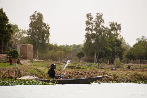 Mujer sacando agua de una canoa en Malí — Foto de Stock