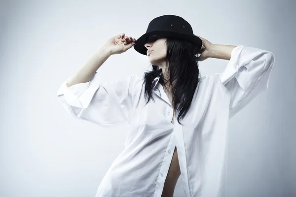 The seductive young brunette in a hat and a shirt — Stock Photo, Image