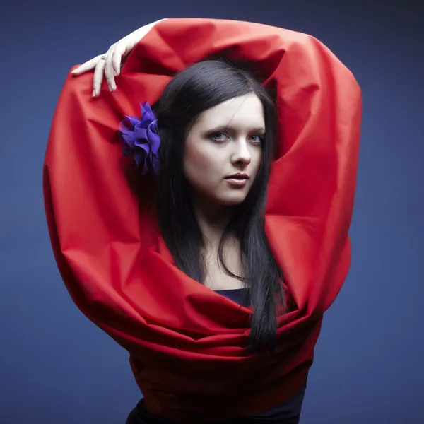 Ritratto della giovane bella donna con un tessuto rosso e un fiore nei capelli timidi — Foto Stock