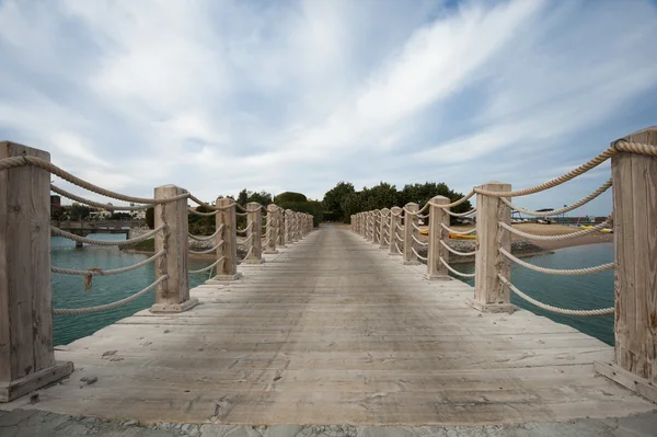 Деревянный мост с веревками над водой — стоковое фото