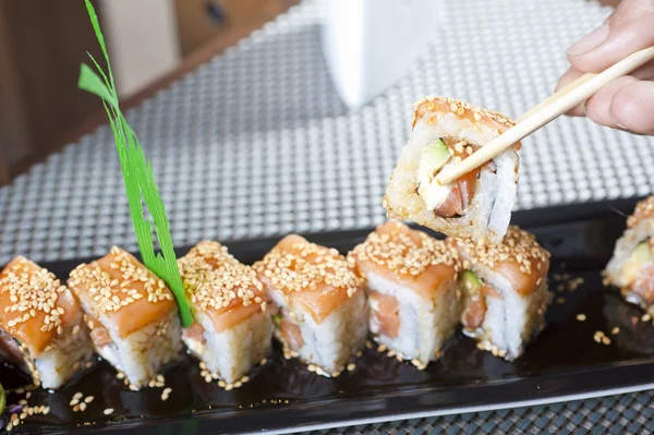 Main à l'aide de baguettes avec sushi — Photo