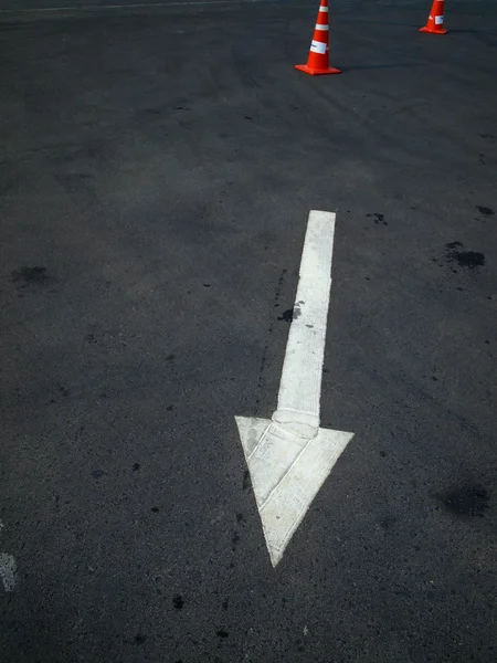 White arrow on the road and orange cone — Stock Photo, Image