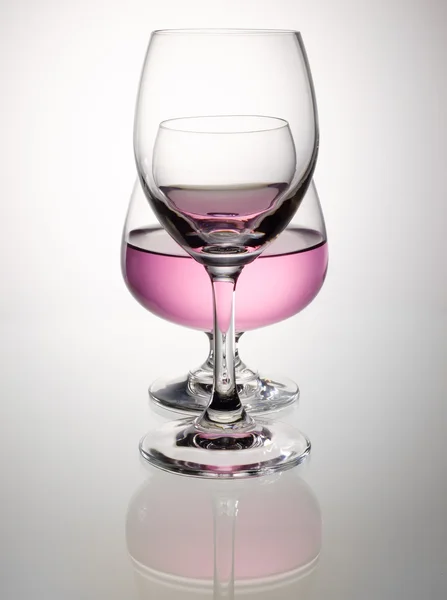 Rosa vin i brandy glas överlappning och reflektion — Stockfoto