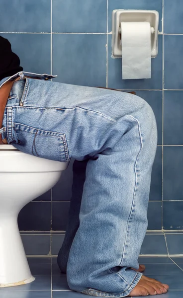 Adam mavi tuvalette oturup — Stok fotoğraf