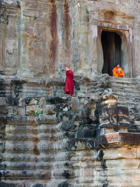 Deux moines bouddhistes non identifiés s'assoient et se tiennent debout à Angkor Wat — Photo
