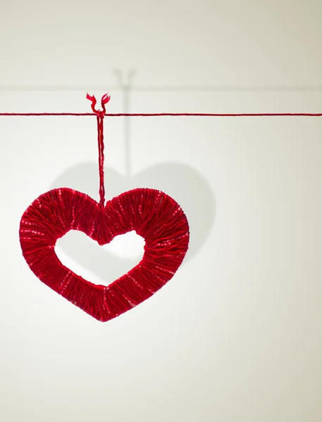 Corazón hecho a mano de hilos rojos cuelga de una cuerda — Foto de Stock