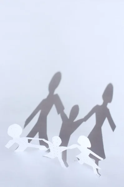 Бумажная цепь: мужчина, женщина и ребенок и тени от них. Ж — стоковое фото