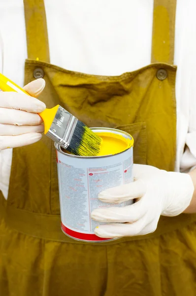 Mujer en caldera maneja cepillo y lata con pintura amarilla —  Fotos de Stock