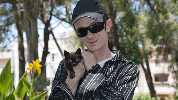 Homem maduro com um gatinho preto — Fotografia de Stock