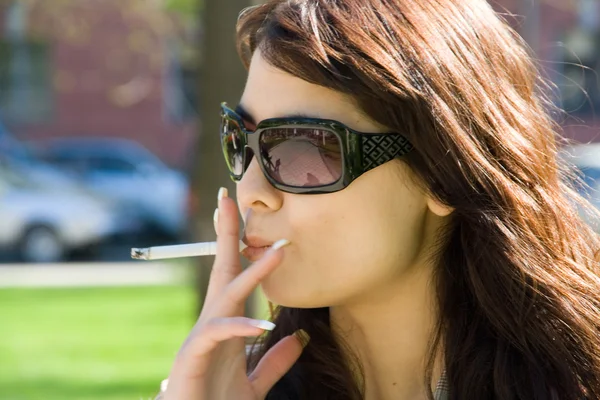 Chica fumadora en gafas de sol Imágenes de stock libres de derechos