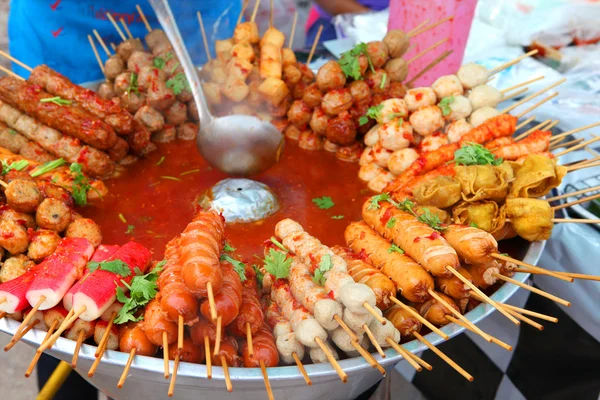 Meat balls and sausages on sticks in a bowl with sauce — Stock Photo, Image