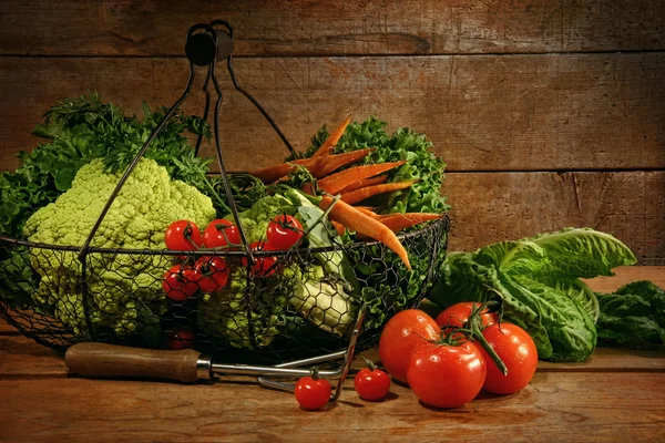 Légumes fraîchement cueillis dans le panier sur une table en bois — Photo