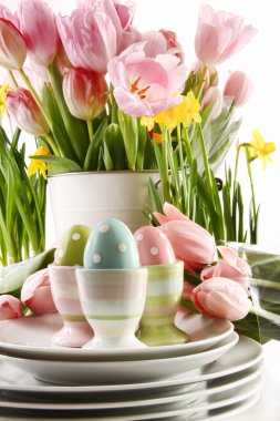 Easter eggs in cups with spring flowers on white clipart