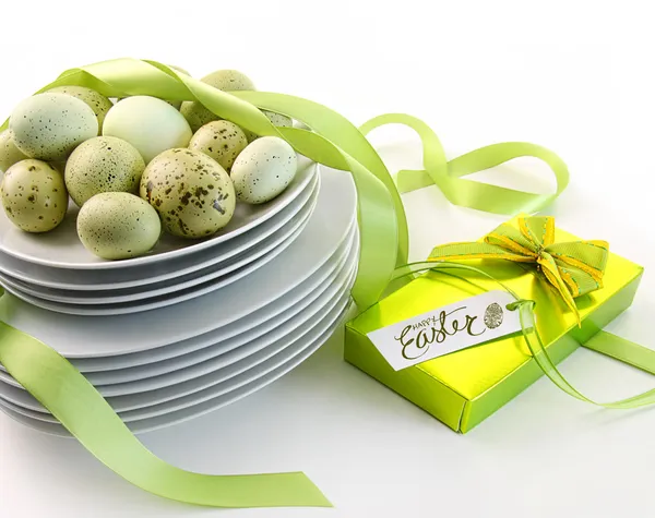Huevos de Pascua en platos con cintas y regalo —  Fotos de Stock