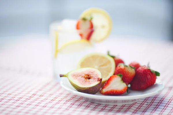 Coquetel com gelo, limão, figo e morangos em um prato — Fotografia de Stock