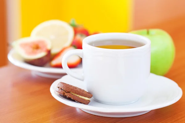 Tasse Tee, Kekse, Apfel, Zitrone, Feige und Erdbeeren auf einem Teller — Stockfoto