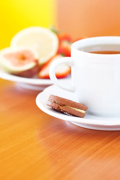 Taza de té, galletas, limón, higo y fresas en un plato —  Fotos de Stock