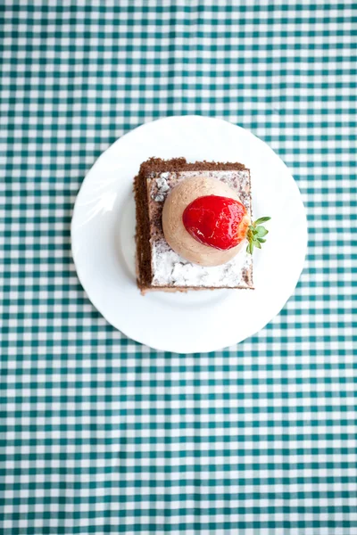 Vacker tårta med jordgubbe på rutigt tyg — Stockfoto