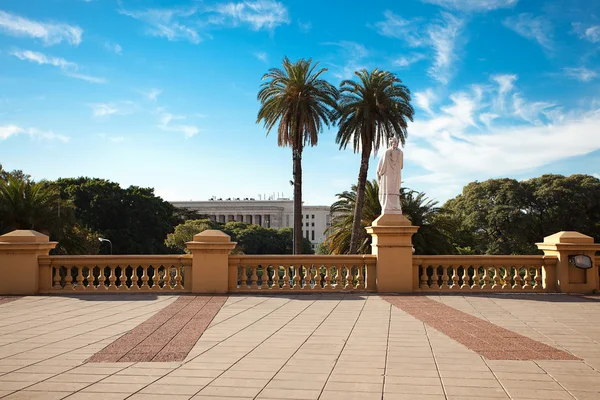 Balcón con una estatua sobre un fondo de palmeras y cielo azul — Foto de Stock