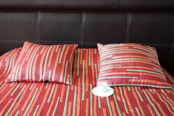 Lit avec deux oreillers, une tasse de thé sur la couverture — Photo