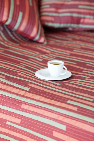 Cama com duas almofadas, uma xícara de chá no cobertor — Fotografia de Stock