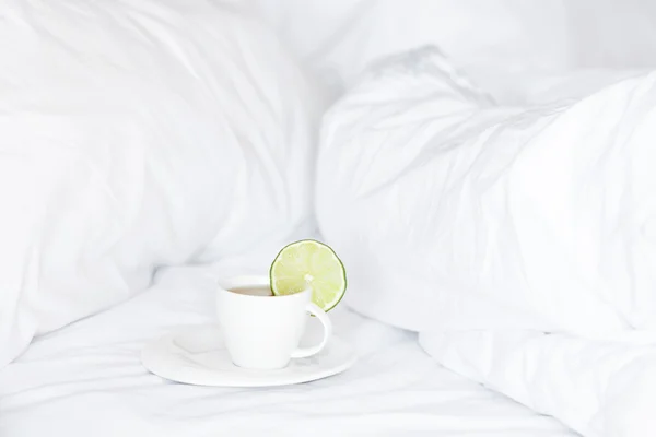 Bett mit einem Kissen und einer Tasse Tee — Stockfoto