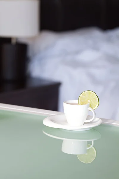 Чай с лимоном на фоне кровати и лампы — стоковое фото