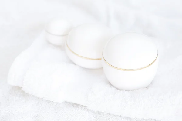 Kosmetiska behållare liggande på vit handduk — Stockfoto