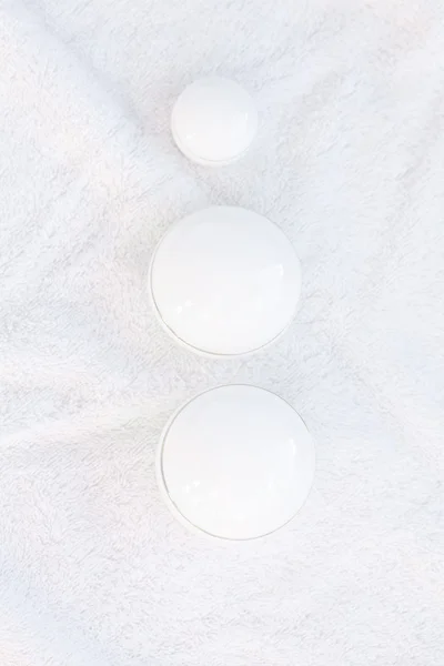 Recipientes cosméticos acostados sobre una toalla blanca —  Fotos de Stock